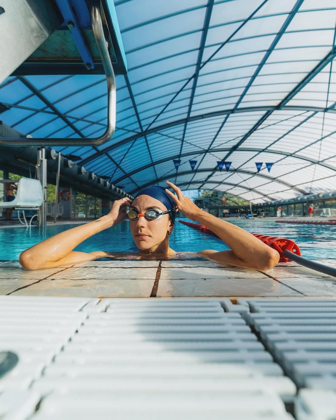 Entraînement en piscine, lunettes en main contre le mur.